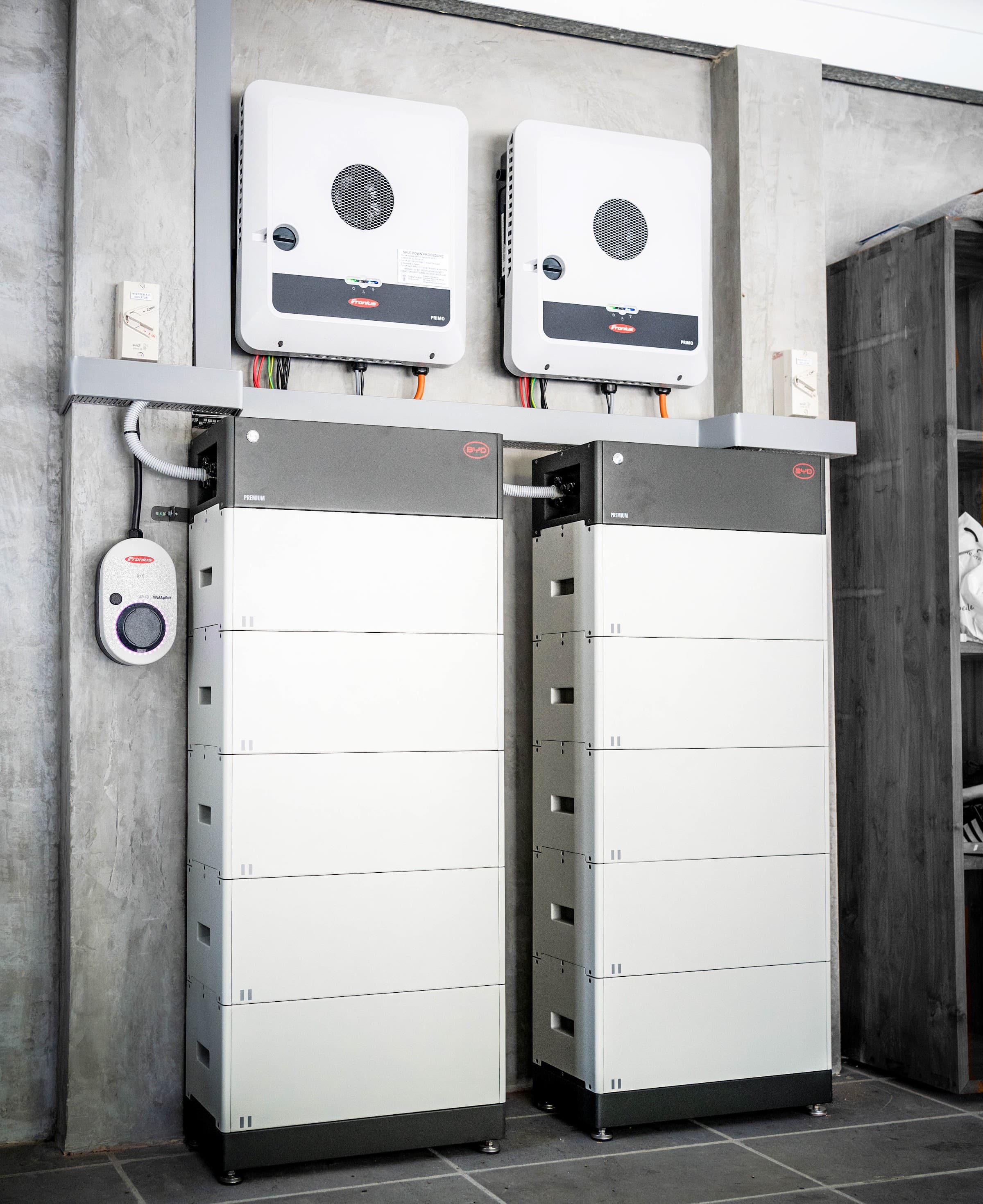 Twin inverters above two battery stacks with a wall-mounted EV charger