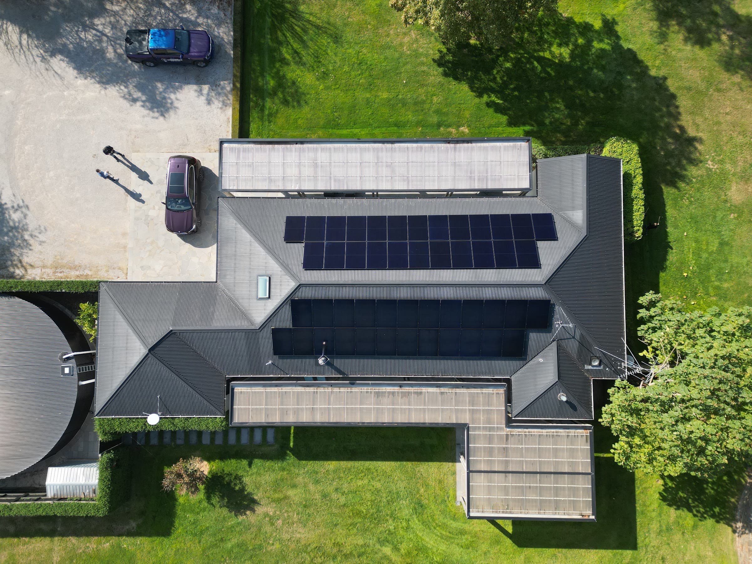 Top-down aerial of a home with black solar arrays laid across the whole roofline